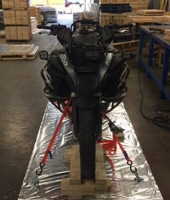 BMW GS adventure bike strapped on a wooden pallet, front view