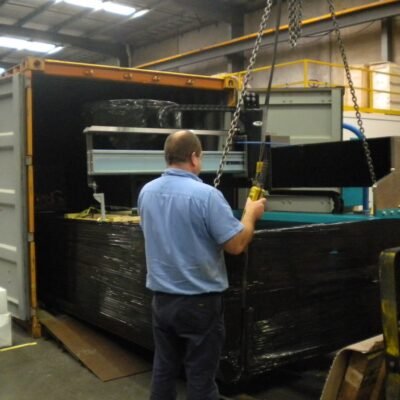 Worker loading wrapped machinery into a shipping container