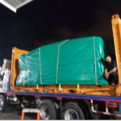Tarp-wrapped cargo on a flatbed truck at night